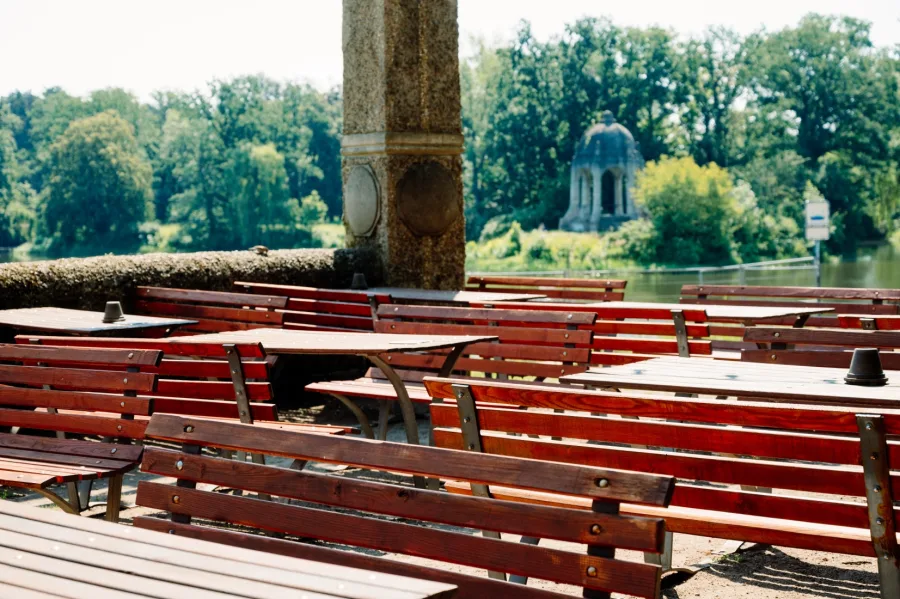 Leere Biergartenb&auml;nke am Adolf-Mittag-See, am gegen&uuml;berliegenden Ufer der Pavillon im Stadtpark