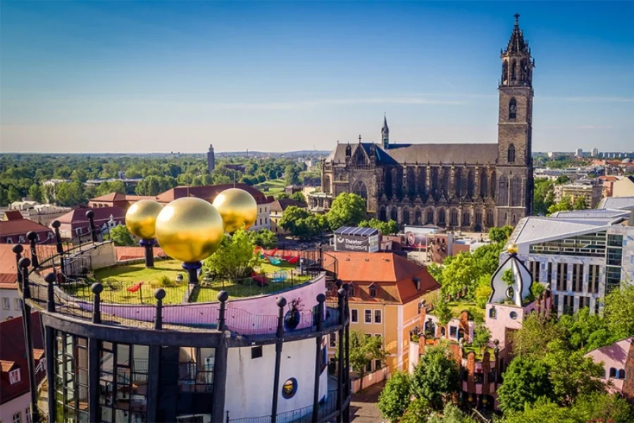 Blick ueber die goldenen Kugeln auf dem Dachgarten der Gruenen Zitadelle zum Magdeburger Dom, dazwischen die Daecher der Altstadt