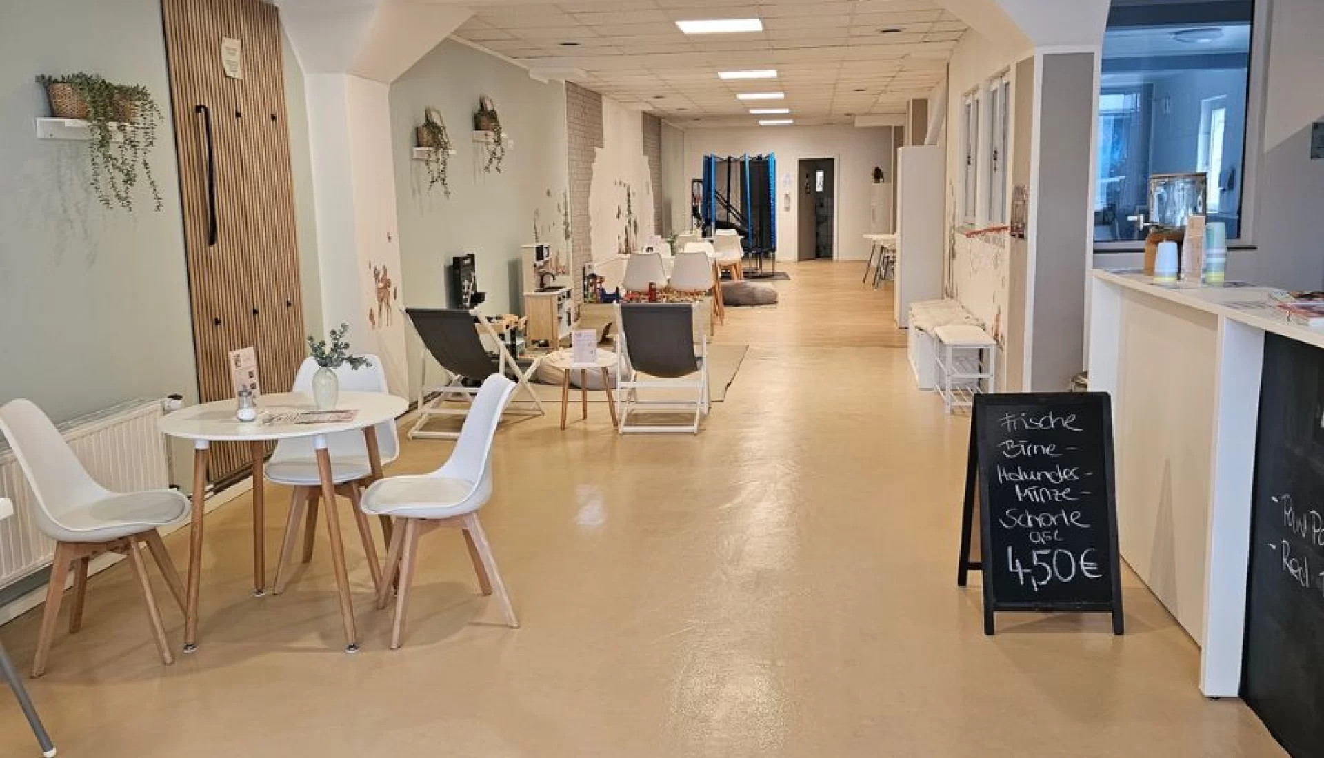 Eltern-Kind-Caf&eacute; im BabyBeach Magdeburg mit Tischen, St&uuml;hlen, einer Theke und weiteren gem&uuml;tlichen Sitzgelegenheiten.