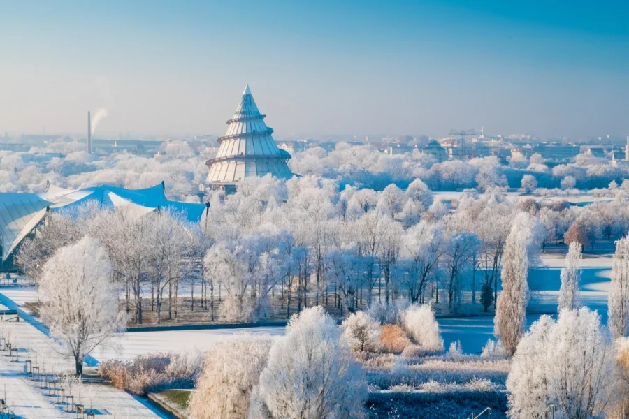 Elbauenpark im Raureif: weiss ueberzogene Baumwipfel um den Jahrtausendturm, links die geschwungenen Daecher der Seebuehne unter blauem Winterhimmel