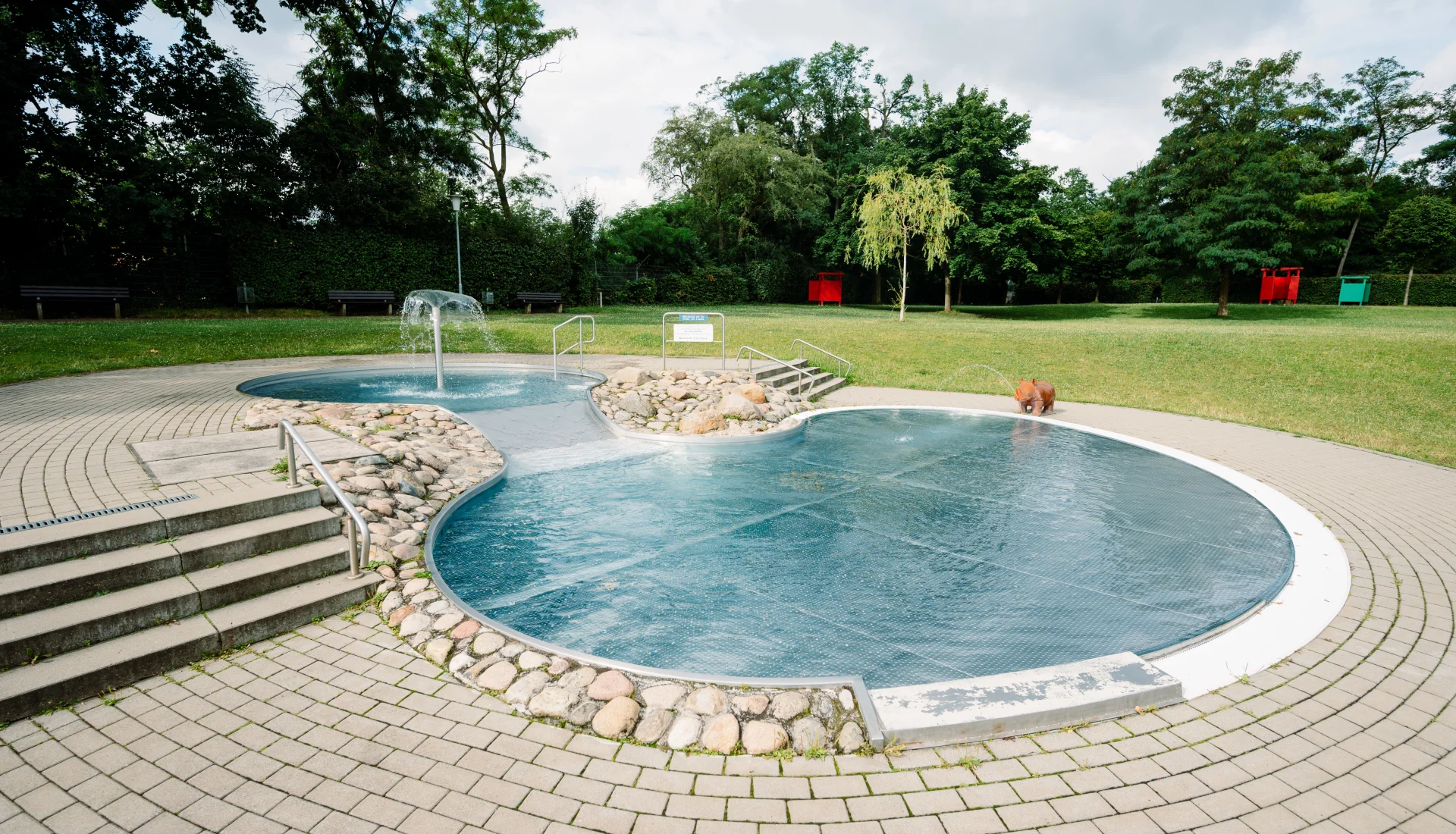 Babyplanschbecken mit Wasserpalme und im Hintergrund gr&uuml;ne Wiese mit M&ouml;glichkeit zum Hinlegen