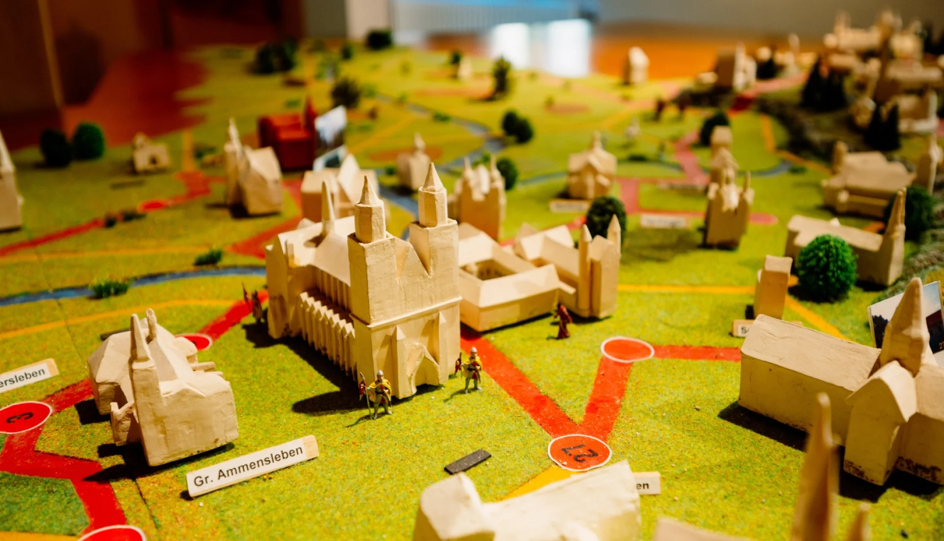 Reliefmodell der Stra&szlig;e der Romanik mit hellen Kloster- und Kirchenmodellen, roten Verbindungswegen und kleinen Ritterfiguren