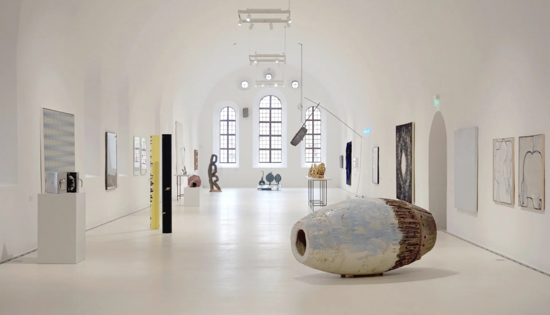 Wei&szlig; get&uuml;nchte Ausstellungshalle des Kunstmuseums mit geh&auml;ngten Arbeiten an den W&auml;nden und einer gro&szlig;en liegenden Keramikskulptur