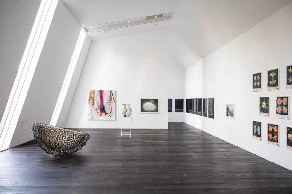 Heller Ausstellungsraum im Nordfl&uuml;gel des Kunstmuseums mit Oberlicht, dunklem Holzboden, geh&auml;ngten Bildern und einer schalenf&ouml;rmigen Drahtskulptur