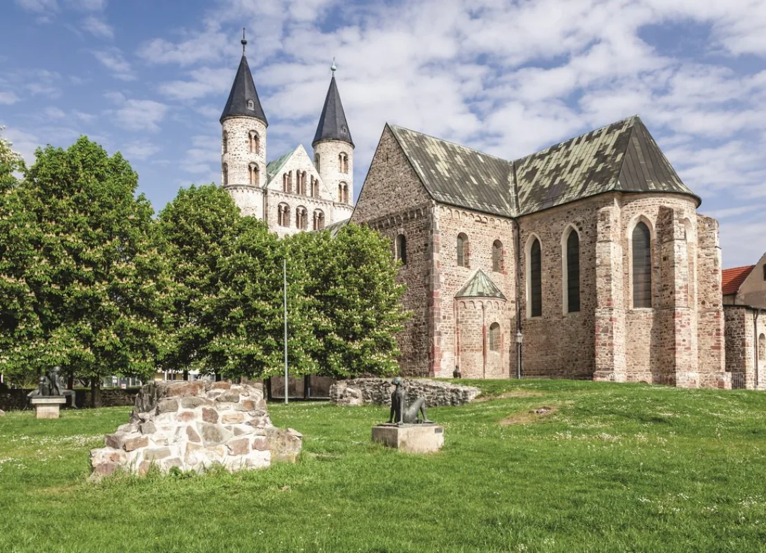 Klosterkirche Unser Lieben Frauen von Osten, davor die Wiese des Skulpturengartens mit Bronzefiguren, Mauerresten und bl&uuml;henden Kastanien