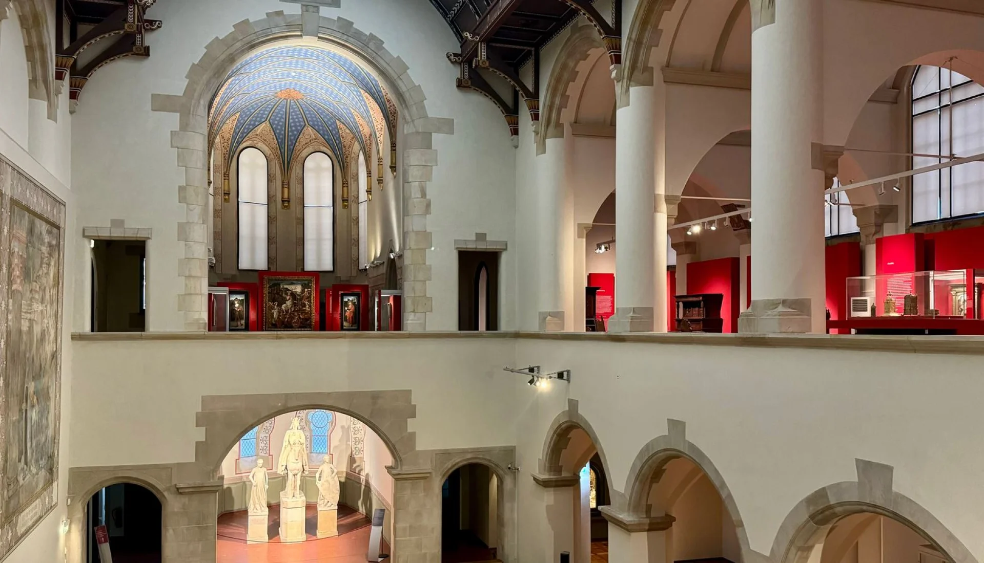 Gro&szlig;e Halle im Kulturhistorischen Museum mit Rundbogenarkaden, blau bemaltem Gew&ouml;lbe, einem raumhohen Wandbild und Skulpturen in der Apsis