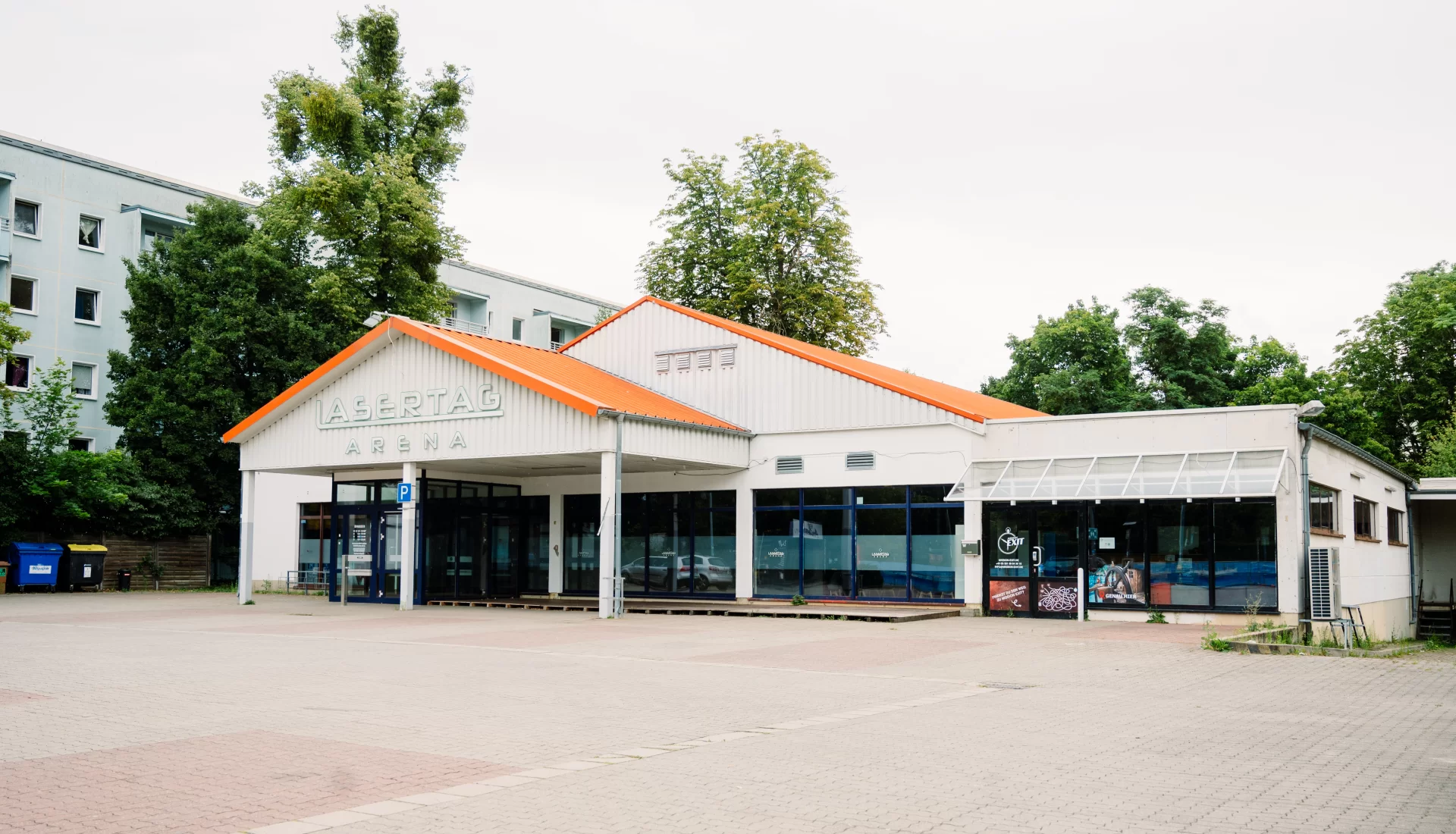 Au&szlig;enansicht der Lasertag Arena Magdeburg mit gro&szlig;em Parkplatz vor dem Eingang.