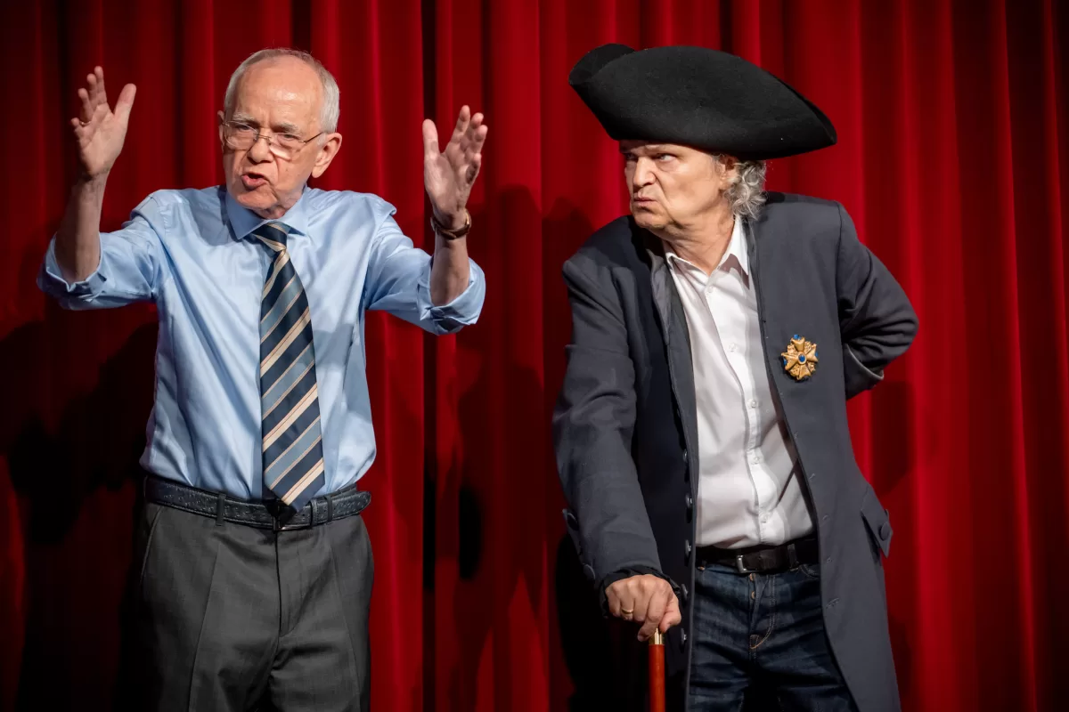 Zwei Darsteller der Magdeburger Zwickmühle auf der Bühne vor einem Roten Vorhang.