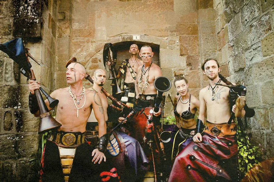 Sechs Musiker der Gruppe Cradem Aventure mit bemalten Gesichtern, Dudels&auml;cken und Schalmeien vor einem steinernen Torbogen